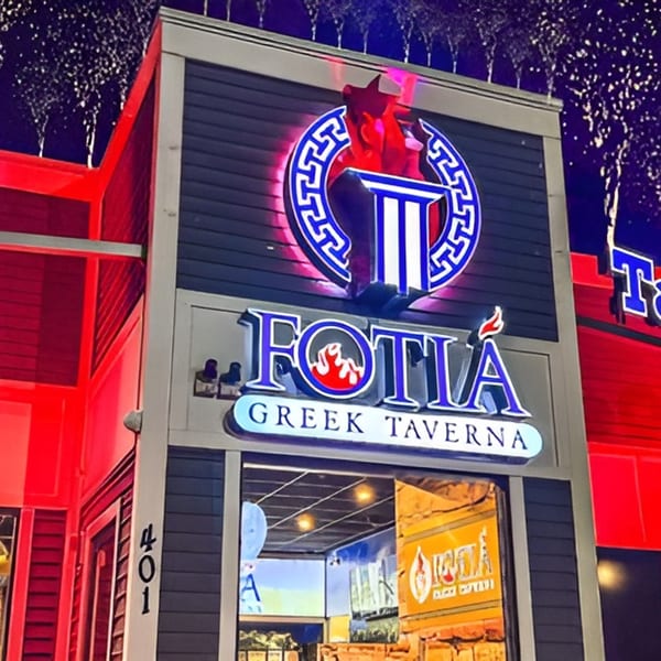 Fotia Greek Taverna's exterior at night, with a prominent neon sign and red lighting.